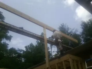 Carpenter setting a ridge beam over a new addition frame — Ice Dam Removal by Roofing Brothers in Paul Smiths