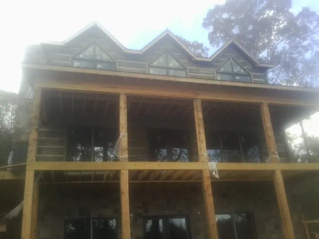 Dormers and porch framing on a large log home under construction — Roof Coating work by our crew in Paul Smiths
