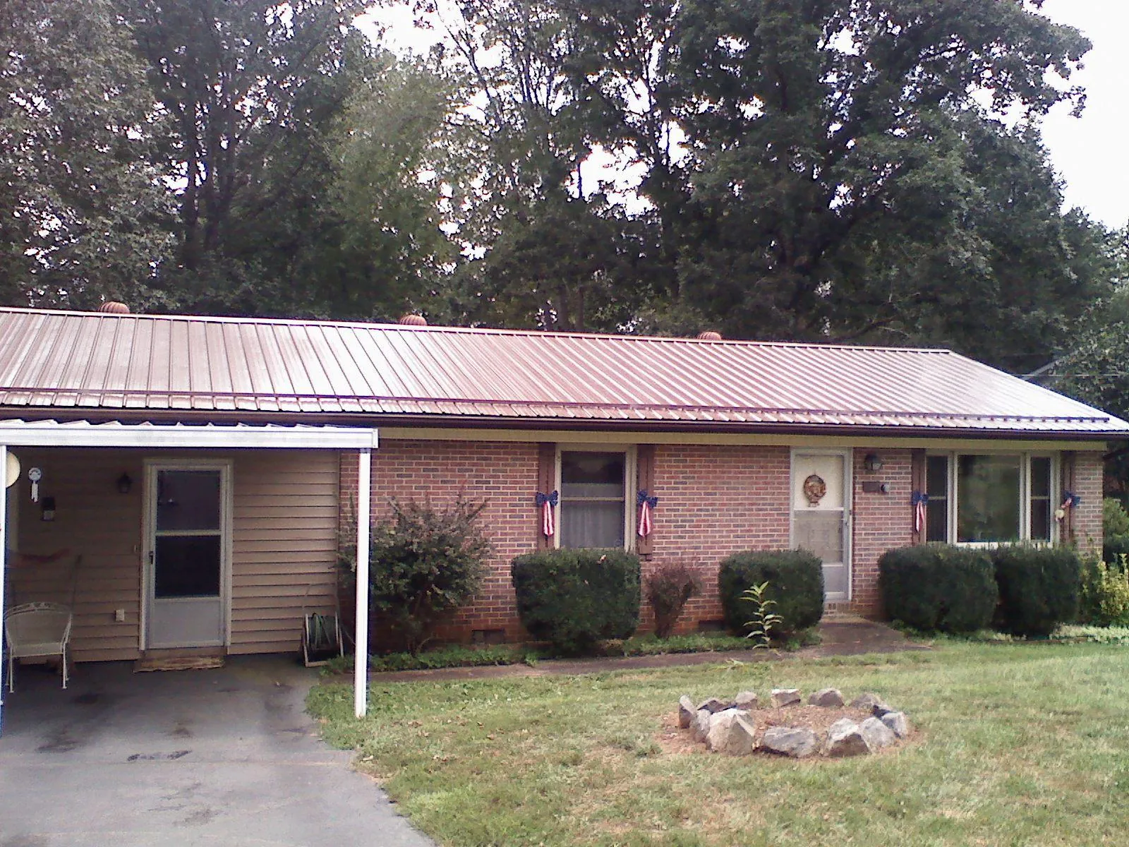 Bronze metal roof and carport on a brick ranch home — Roof Repair work by our crew in Paul Smiths