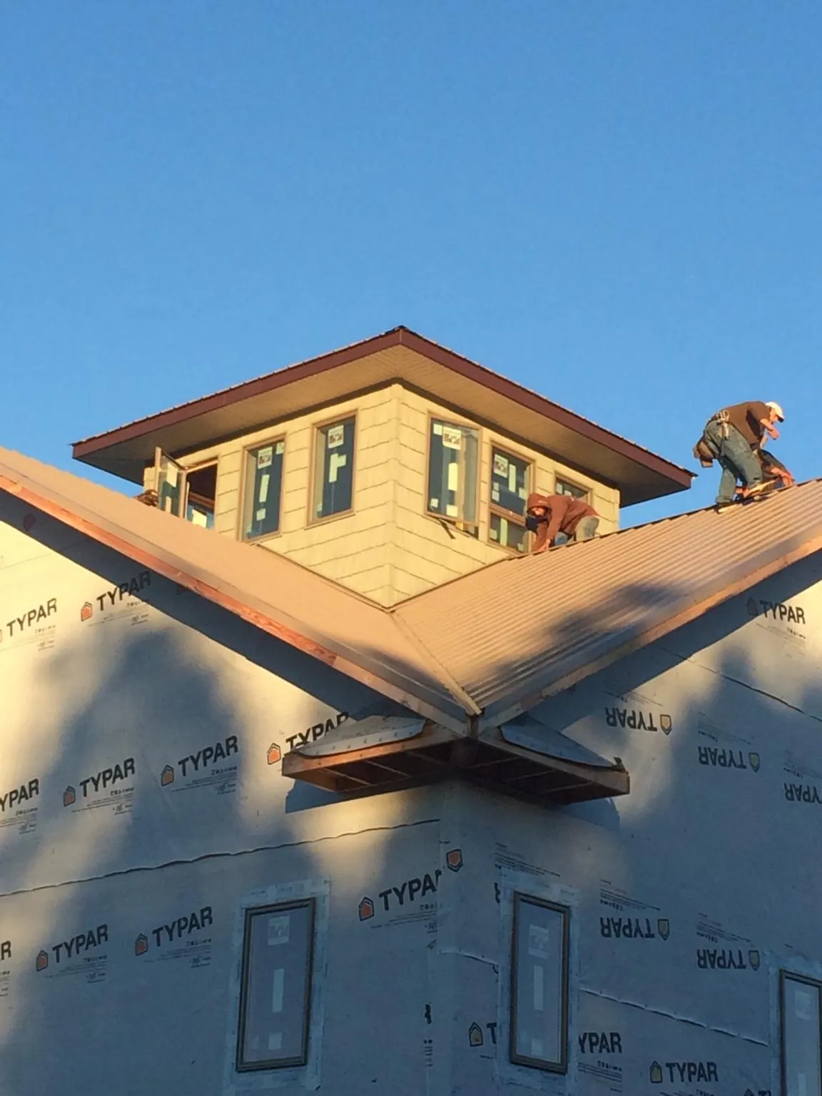 Roofers working around a rooftop cupola on a new metal roof at sunset — Roof Waterproofing in Paul Smiths by Roofing Brothers